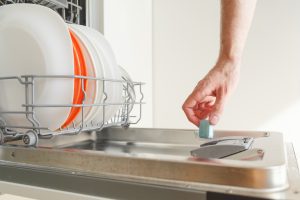 Man puts a chemical dishwasher tablet into the dishwasher machine in Dover FL